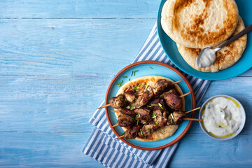 Greek souvlaki with pita bread and tzatziki sauce on a blue wooden background.Copy space