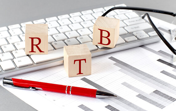 RTB written on a wooden cube on the keyboard with chart on grey background