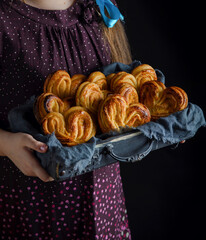 Little girl holding wooden tray with homemade sugar buns. Close up - 612799686