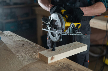 Master cuts the board with a circular saw in the workshop. Close-up of a carpenter's hands at work. 