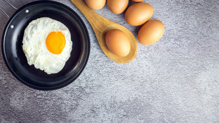 Top view of Breakfast menu fried eggs in an iron pan and raw chicken eggs.