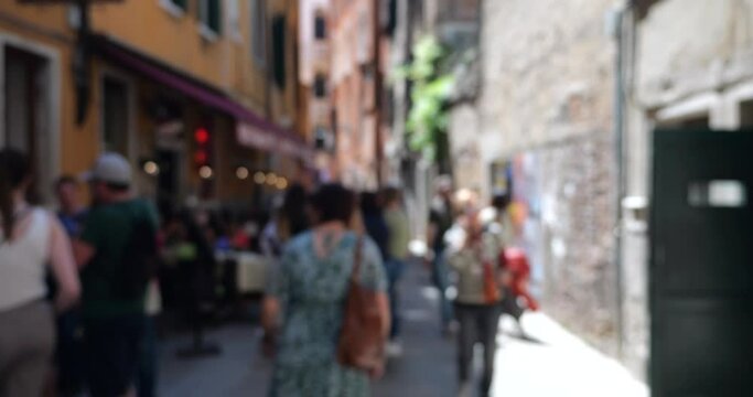 Tourists at the one of the ancient streets in Venice, Italy on a clear spring day. Out of focus.