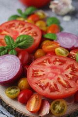 Flat lay composition of different tomatoes, onion, basil and garlic