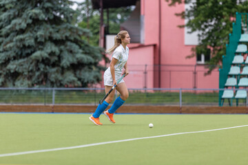 Fototapeta premium Field hockey female player leading the ball in attack. Young woman playing in field hockey tournament