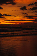 Fototapeta na wymiar Amazing bright orange sunset on the Indian Ocean with waves on Bali island. Evening sunlight, fire sky