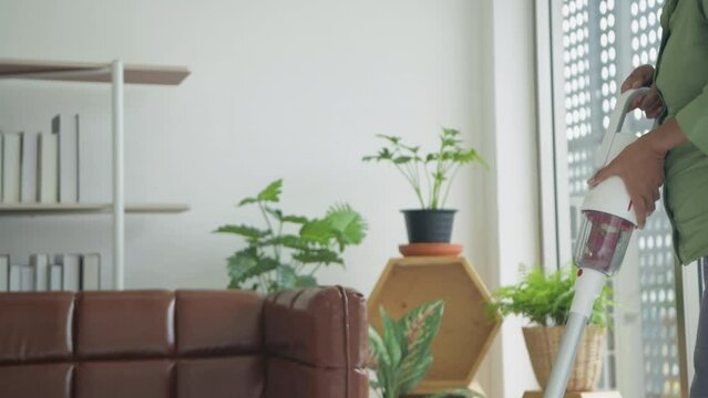 Holiday concept of 4k Resolution. An Asian old woman vacuuming inside the living room.