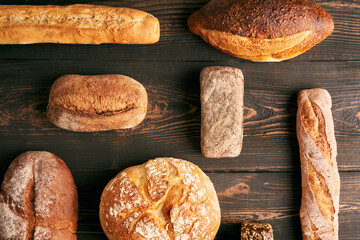 Different types of bread loaves on dark wooden background