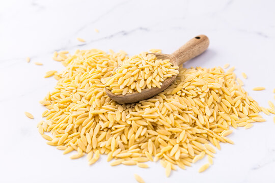 Raw orzo pasta (risoni) with wooden spoon