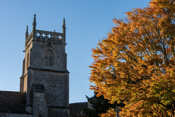 Ancient church tower with trees with Autumn leaves in foreground