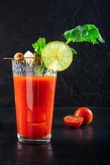 Bloody Mary cocktail with garnish on a black background. Spicy tomato juice with alcohol, lime, and...