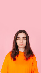 Fototapeta premium Pretty in Pink: Charming Young Woman in Stylish Orange T-Shirt on Isolated Pink Background. Fashionable and Vibrant Concept.