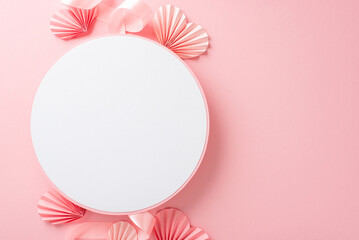 Top view photo of empty white circle with a pastel pink ribbon and paper origami hearts on an...