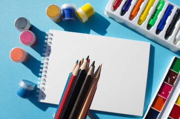 Tools for painting brush colored pencils of various types paints blank with easel flatley style on blue background Copy space mockup Art concept learning to draw Baner style Greeting card Hobby Relax