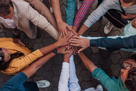 Top view photo of a group of business people and colleagues standing together holding hands, looking towards the camera, symbolizing unity and teamwork.