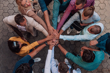 Fototapeta na wymiar Top view photo of a group of business people and colleagues standing together holding hands, looking towards the camera, symbolizing unity and teamwork.