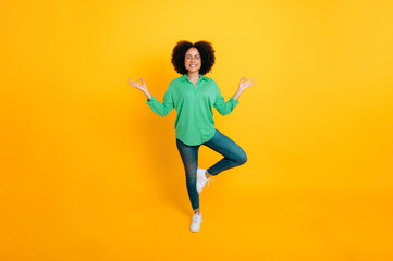 Fototapeta na wymiar Mental health, harmony. Full length photo of a stylish lovely calm african american or brazilian curly woman meditating while standing tree pose with closed eyes on isolated yellow background