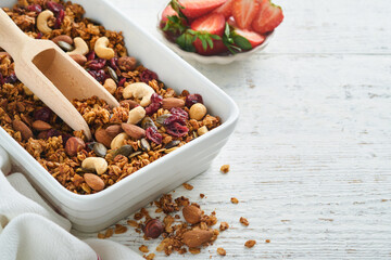 Homemade granola with greek yogurt or milk and cashews, almonds, pumpkin with dried cranberry seeds in old bowl on white rustic wooden table background. Healthy energy breakfast or snack. Top view.