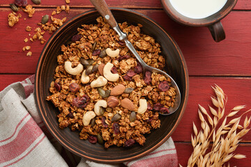 Homemade granola with greek yogurt or milk and cashews, almonds, pumpkin with dried cranberry seeds in old bowl on red rustic wooden table background. Healthy energy breakfast or snack. Top view.