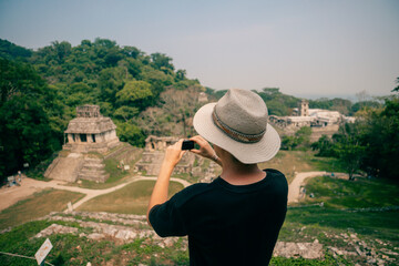 Hiker man with a hat looking at ancient Mayan ruins