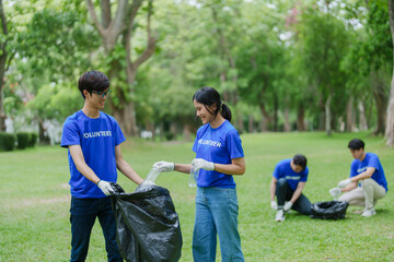 Multiethnic volunteers donate their time holding black garbage bags to collect plastic waste for recycling to reduce pollution in a public park.
