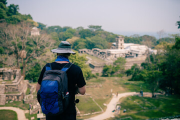 Hiker man with a hat looking at ancient Mayan ruins