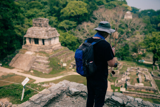 Hiker man with a hat looking at ancient Mayan ruins
