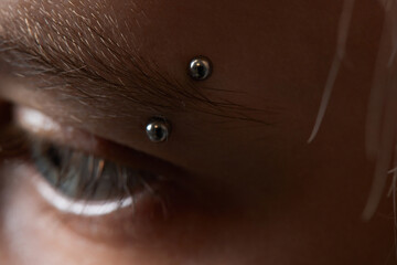 Professional placing the jewel of piercing on the temple on the head with ball. Tragus type.