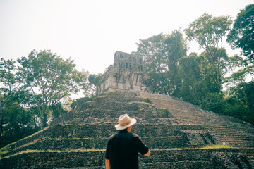 Fototapeta na wymiar Hiker man with a hat looking at ancient Mayan ruins