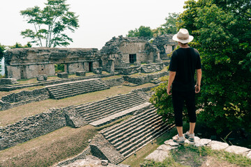Hiker man with a hat looking at ancient Mayan ruins
