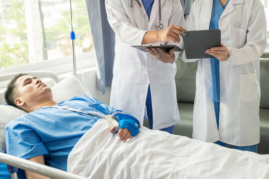 Two doctors talking to a patient lying in bed while receiving saline solution in hospital Professional medical service concept Attentive doctor comforting a patient Stock Picture