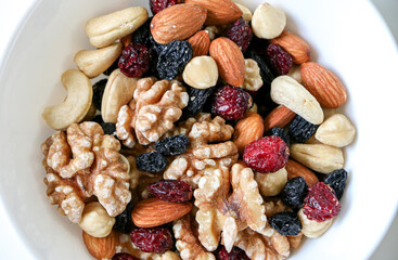 A healthy diet, close up of a bowl of mixed dried fruits and nuts consisting of almonds, walnuts, hazelnuts, cashew nuts, raisins and cranberries. Healthy food concept.