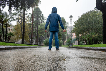 Man standing back to back in the rain in a city park. Autumn, rain and bad weather.