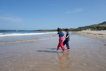 Young girls holding hands on the beach