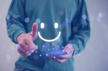 Customer service satisfaction survey concept.Business people or customers show satisfaction by pressing face emoticon smile in satisfaction on virtual touch screen. thumb up