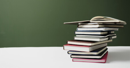 Close up of stack of books with copy space on green background