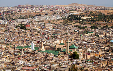 Aerial city view of the old Medina (downtown neighborhood) and the minaret of Zaouia Moulay Idriss II in Fez, Morocco, Africa. Rooftop view of Mosque towers and traditional Arabic townhouses.