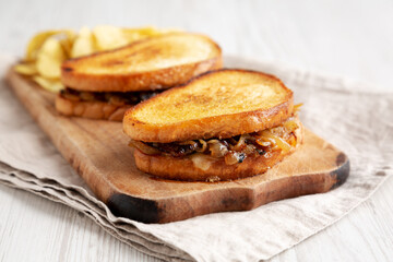 Homemade French Melt Sandwich with Caramelized Onion and Gruyure Cheese on a rustic wooden board, side view. Close-up.