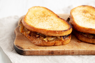 Homemade French Melt Sandwich with Caramelized Onion and Gruyure Cheese on a rustic wooden board, side view. Close-up.