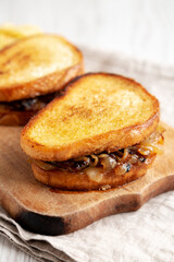 Homemade French Melt Sandwich with Caramelized Onion and Gruyure Cheese on a rustic wooden board, side view. Close-up.