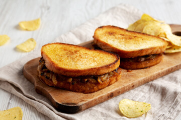 Homemade French Melt Sandwich with Caramelized Onion and Gruyure Cheese on a rustic wooden board, side view.