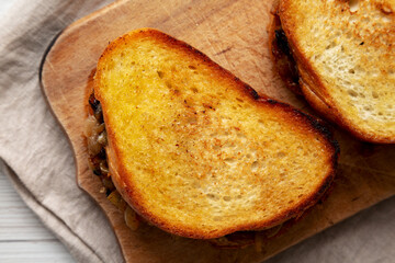 Homemade French Melt Sandwich with Caramelized Onion and Gruyure Cheese on a rustic wooden board, top view. Flat lay, overhead, from above.