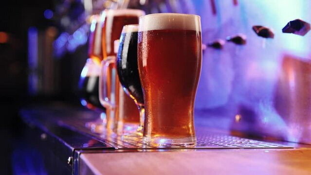Close-up image of beer glasses with dark and lager beer in neon. Selective focus. Cool, chill drink. Refreshment. Bar, pub atmosphere. Concept of alcohol drink, party, taste, relaxation. Ad