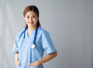 Portrait of young female doctor smiling to the camera while standing with white background.