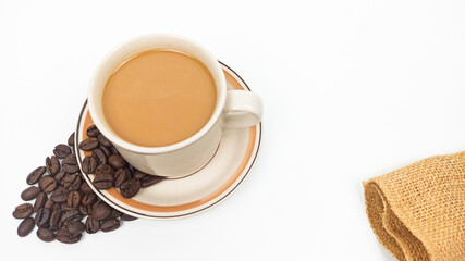 Cup of coffee with coffee beans isolated on white background. Milk coffee or caffe latte in a mug beside a pile of beans against a white background.
