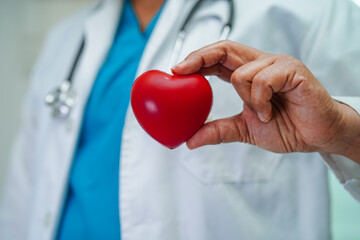 Asian woman doctor holding red heart for health in hospital.