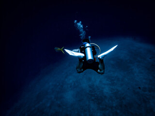 Scuba diver reaches the bottom of the ocean floor at Lost Blue Hole 160' underwater in the Exuma Cays, Nassau, Bahamas