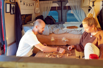 caucasian couple playing a board game inside their camper trailer