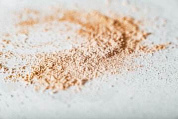 crumbly compact make-up powder in a nude tone with a large powder brush on a white background. Macro, close-up