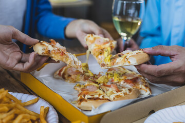 Colleague hands and friends eating pizza After a long meeting, They are having party at home office, eating pizza and having fun. leisure, food and drinks, people and holidays.