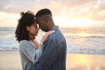 Young multiethnic couple standing in each other's arms on a beach at sunset